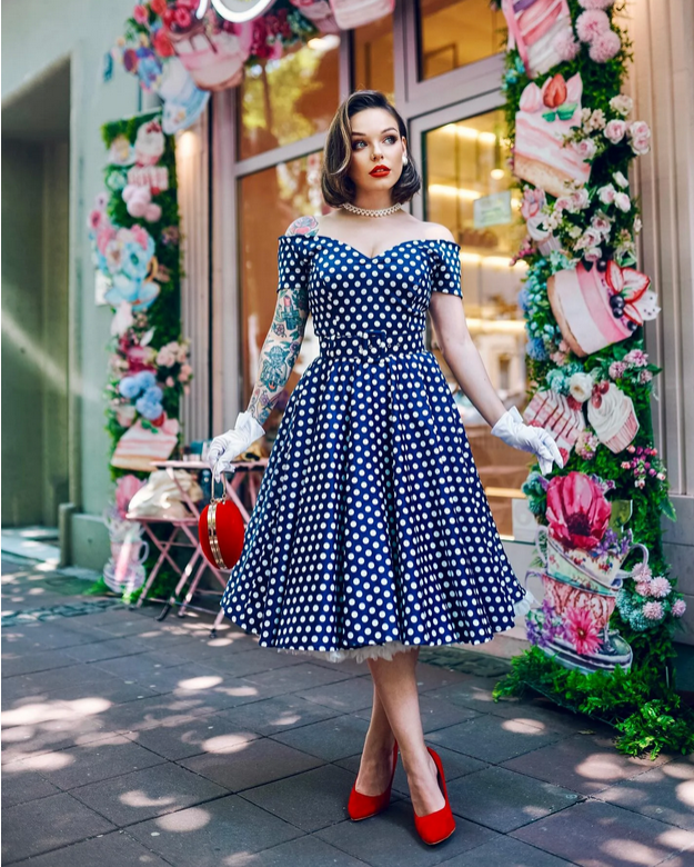 Navy blue pin-up polka dot dress styled with red heels and gloves